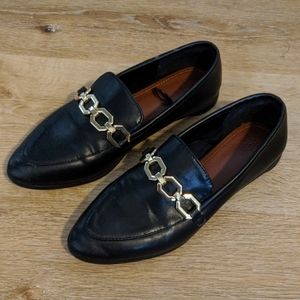 Black loafers with gold chain accent